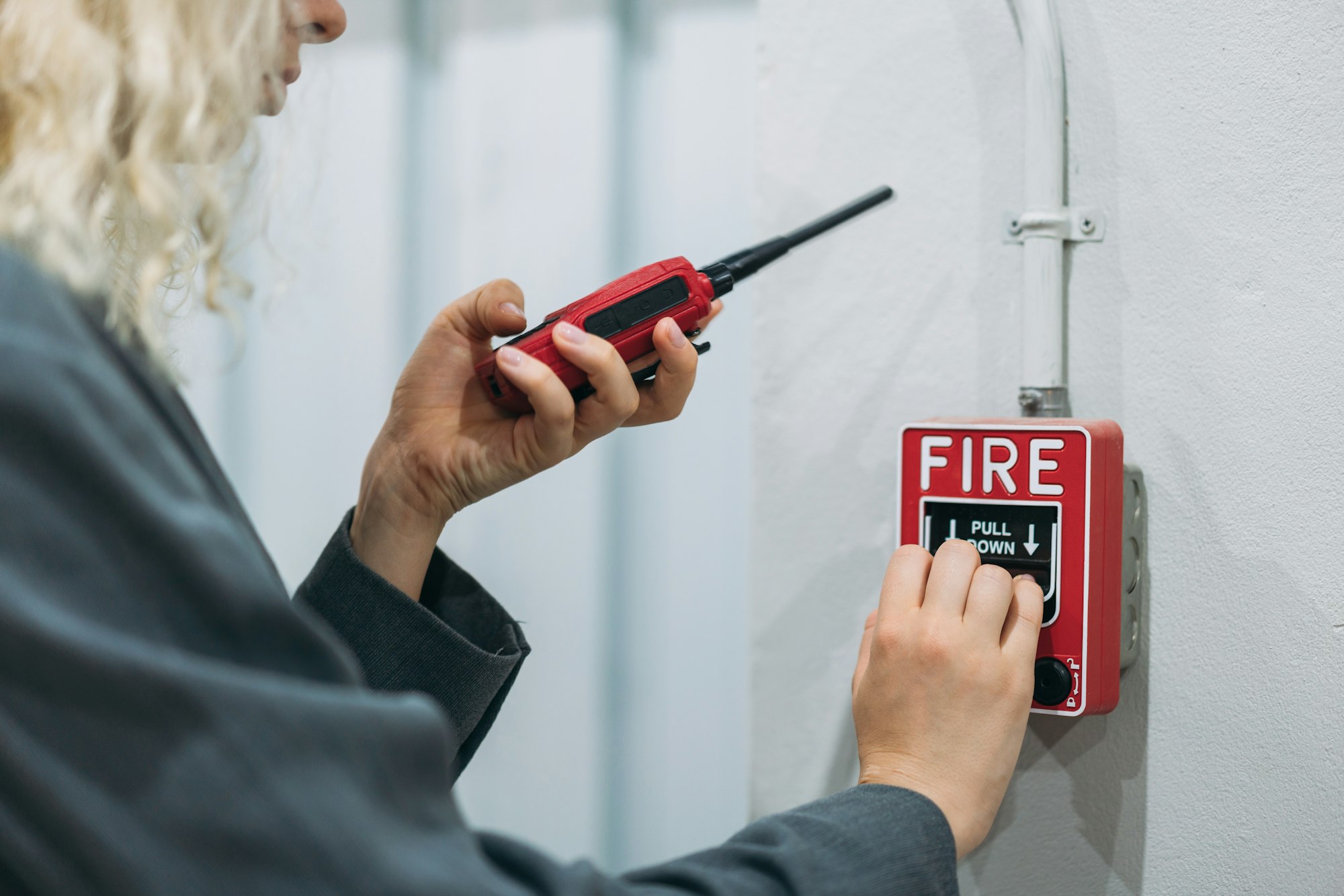 Mitarbeiterin löst einen Feueralarm aus und hält dabei ein Funkgerät in der Hand